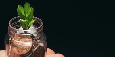 Hand holding money jar with plant inside
