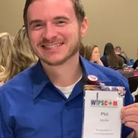 male with blue shirt and badge at conference.