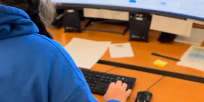 female in blue uniform in front of dispatch computer screens